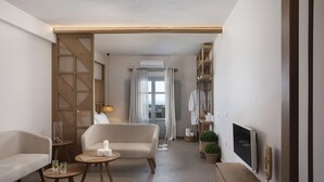 A modern living room with a sofa, a coffee table, a TV, and a wooden cabinet. - New Villa Katerina Collection (Santorini)