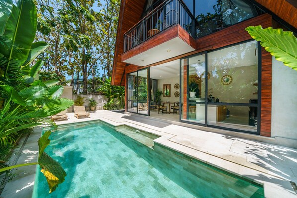A modern house with a swimming pool, large windows, and a balcony.