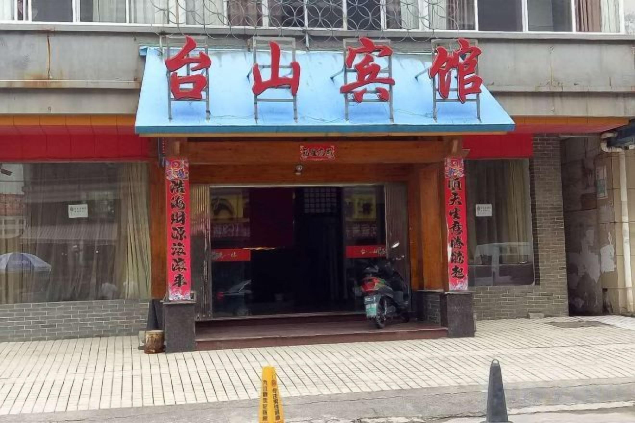 A hotel with a blue awning and red signage.