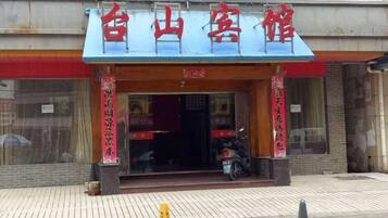 A hotel with a blue awning and red signage.