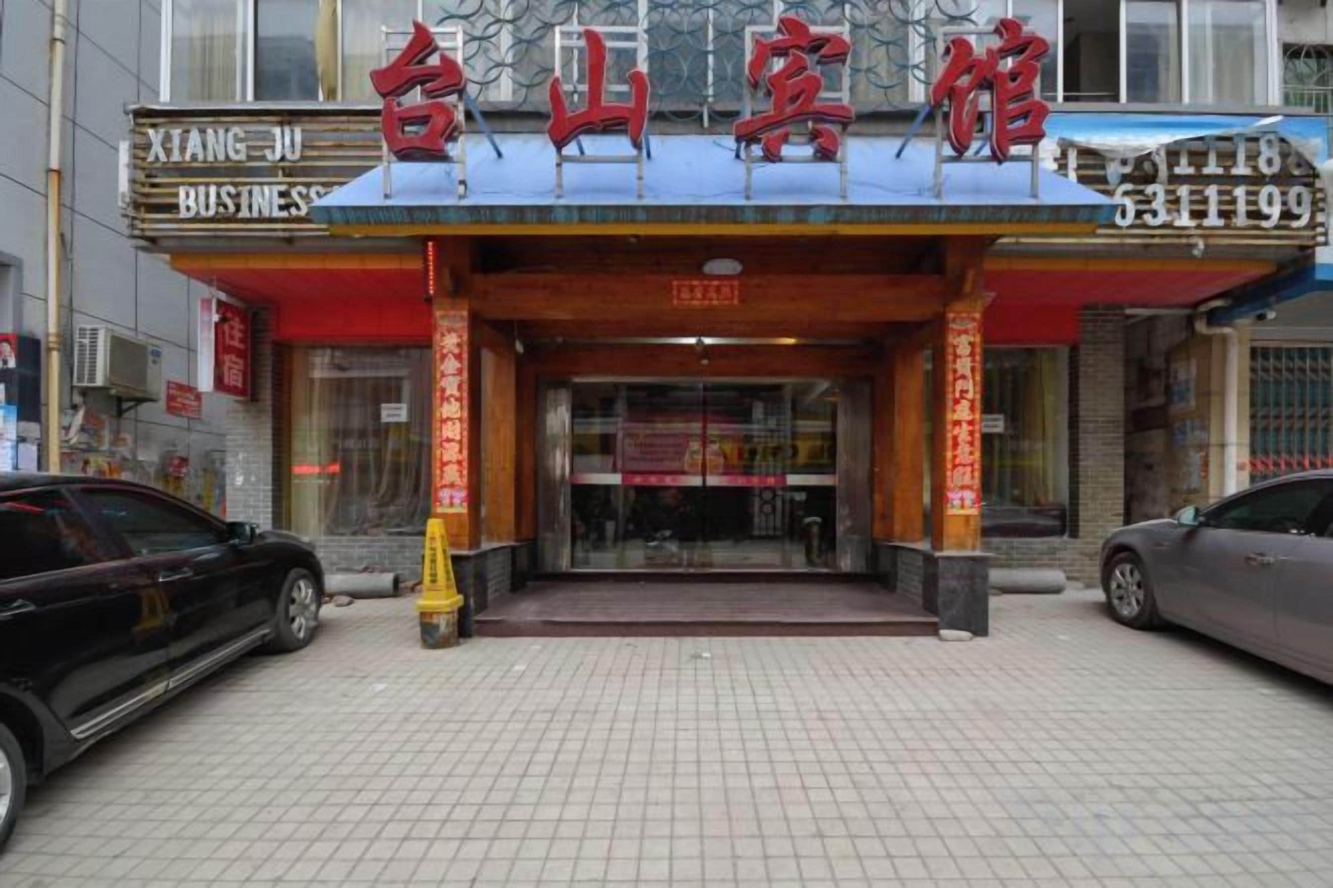 A hotel entrance with a tiled ground, a red awning, and a sign with Chinese characters.