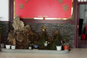 A decorative wall with a red backdrop and a stone arrangement. - Taishan Hotel (Hukou)