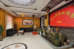 A hotel lobby with a reception desk, seating area, and decorative plants. - Taishan Hotel (Hukou)
