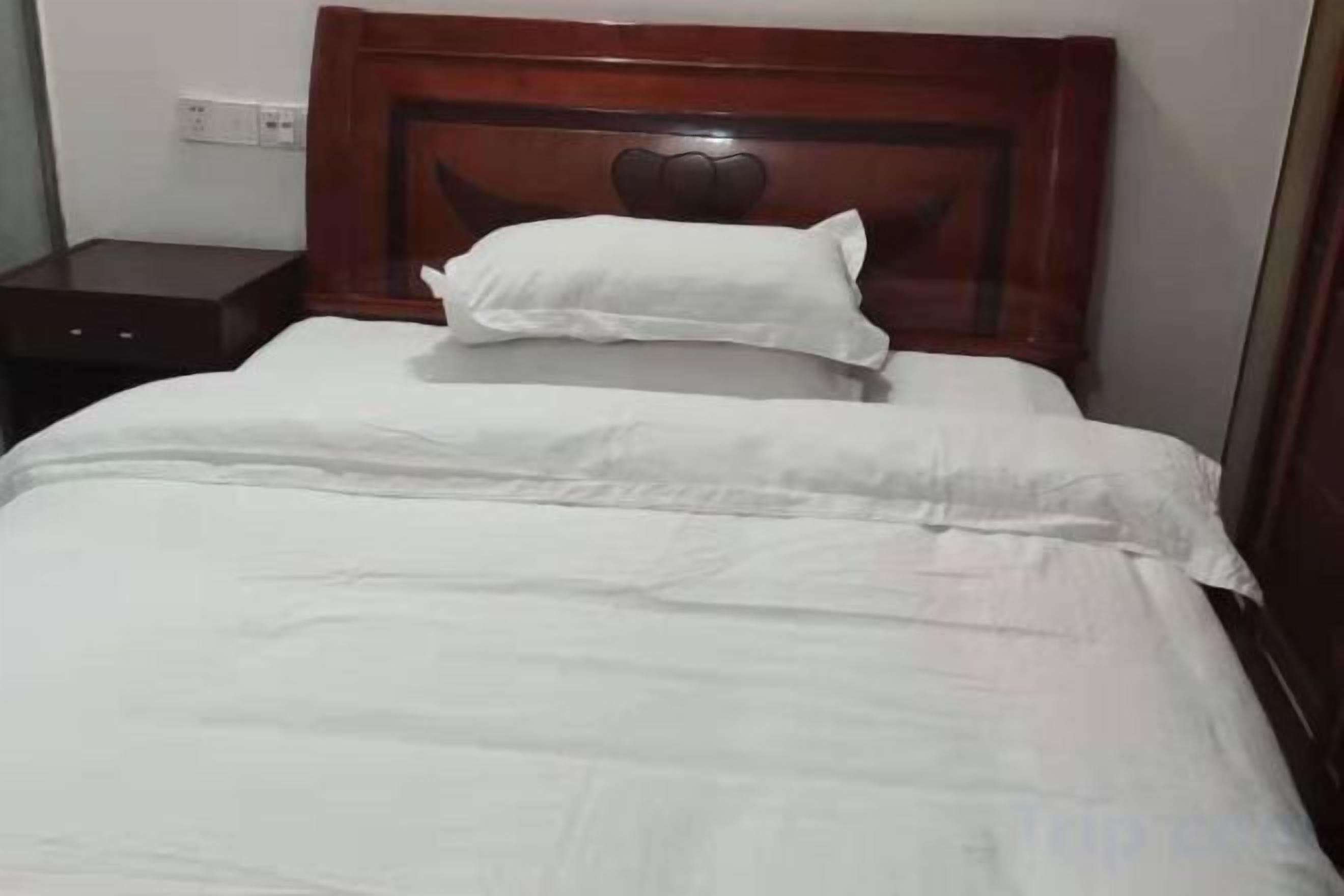 A bed with a wooden headboard and white bedding.