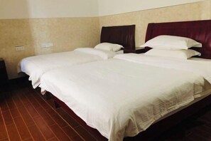 A hotel room with two beds, each with white linens and dark headboards.