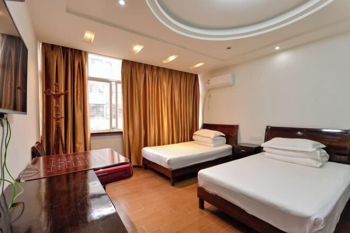 A hotel room with two beds, a desk, and a window with curtains.