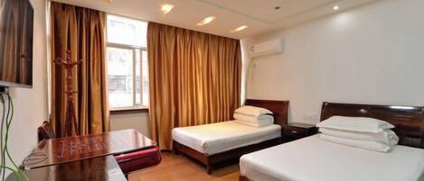 A hotel room with two beds, a desk, and a window with curtains.