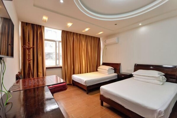 A hotel room with two beds, a desk, and a window with curtains.