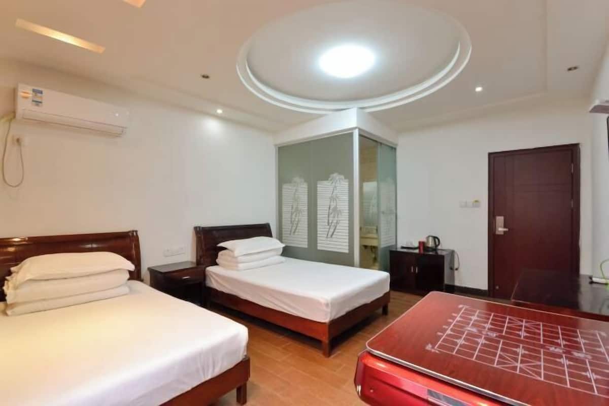 Une chambre d’hôtel avec deux lits, un bureau, une armoire et un luminaire au plafond.