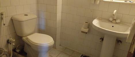 Un baño con inodoro, lavamanos y paredes de cerámica.
