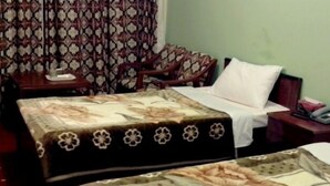 A hotel room with two beds, a desk, a chair, and a television. - Hotel Al Bader (Mekhtar)