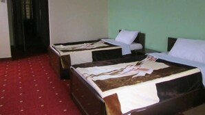 A room with two beds, a red carpet, and a green wall. - Hotel Al Bader (Mekhtar)