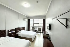 Habitación de hotel con dos camas, un escritorio, una silla y un televisor montado en la pared.