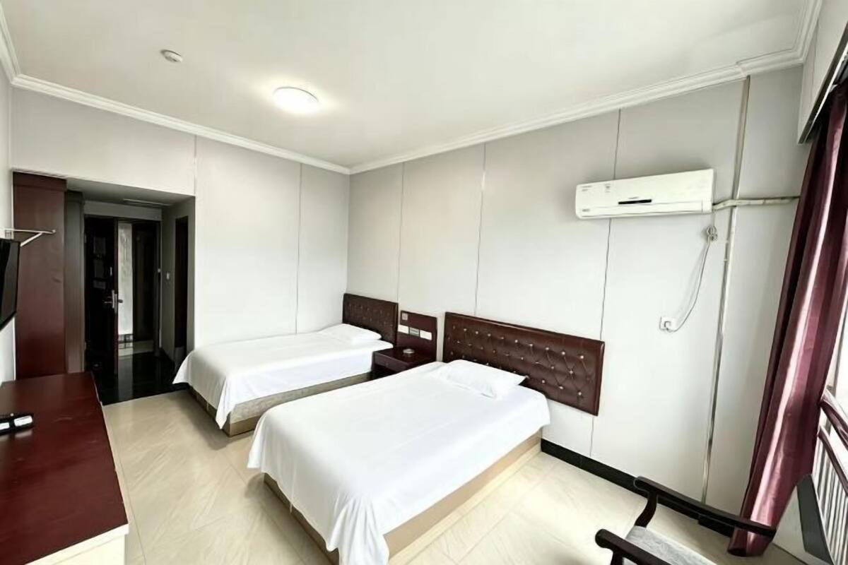 Habitación de hotel con dos camas, un escritorio y una televisión.