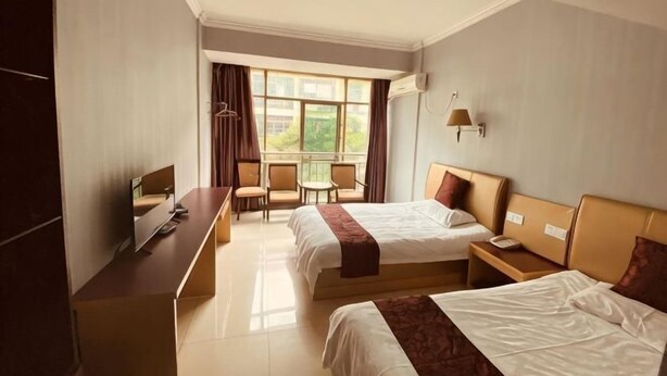 Une chambre d’hôtel avec deux lits, un bureau, une chaise et une fenêtre avec des rideaux.