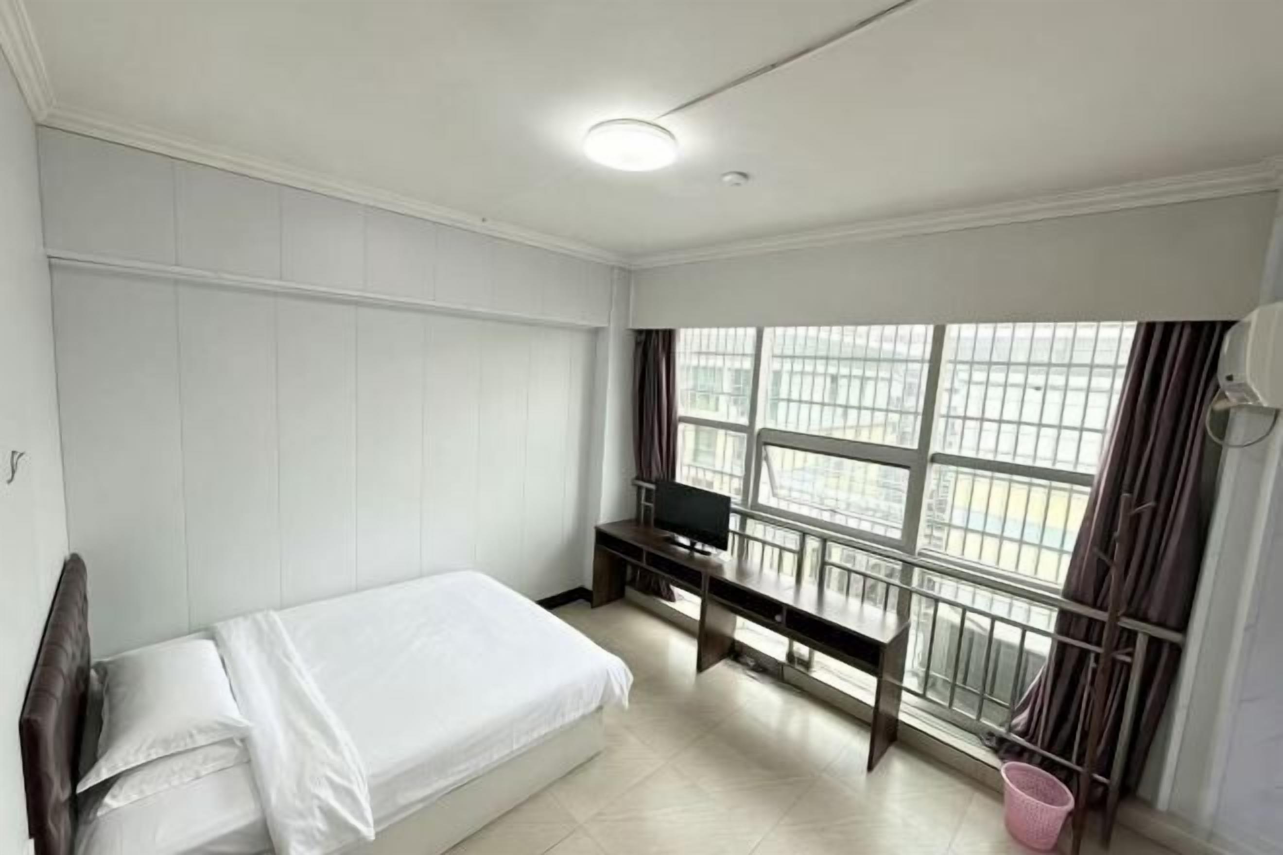 A bedroom with a bed, a desk, and a TV.