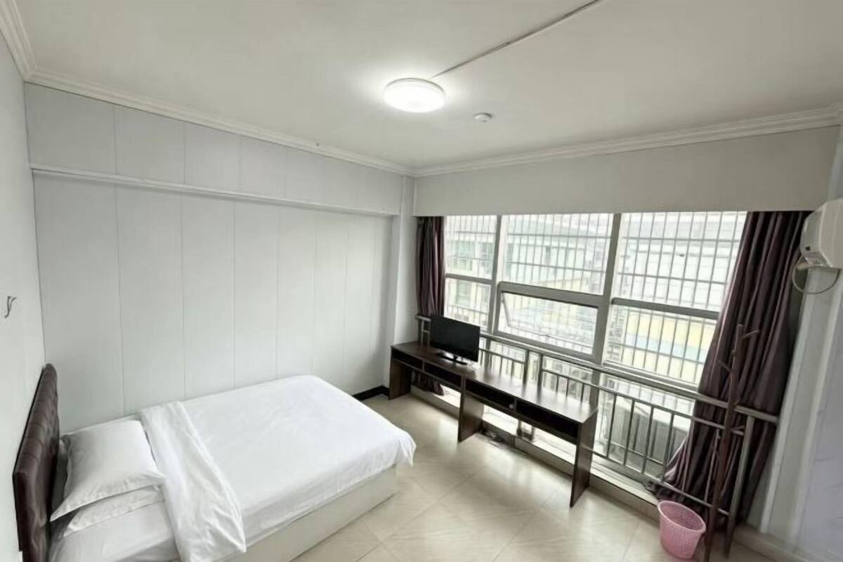 Un dormitorio con cama, escritorio y televisor.