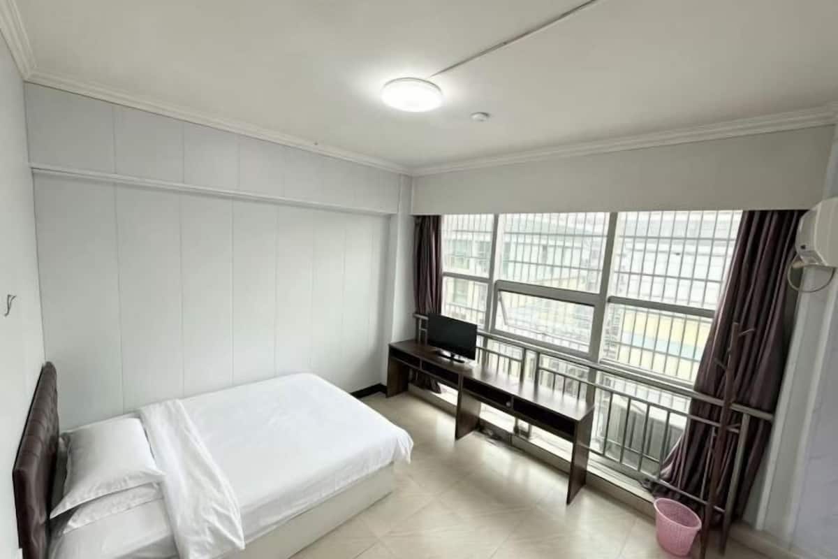A bedroom with a bed, a desk, and a TV.