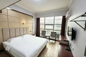 A hotel room with a large bed, a desk, two chairs, a TV, and a window with a city view. - Chuang Wang Fu Hotel (Yiwu)