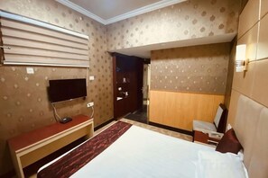 A hotel room with a bed, a desk, a TV, and a wardrobe.