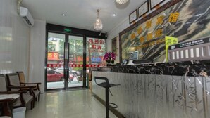 Un espace d’accueil d’hôtel avec un comptoir en marbre, un fauteuil moderne et une porte vitrée donnant sur l’extérieur.