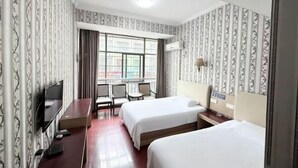 Une chambre d’hôtel avec deux lits, un bureau, une télévision et une fenêtre avec des rideaux.