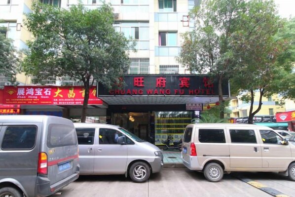 A hotel entrance with signage, parked vehicles, and a building facade. - Chuang Wang Fu Hotel (Yiwu)