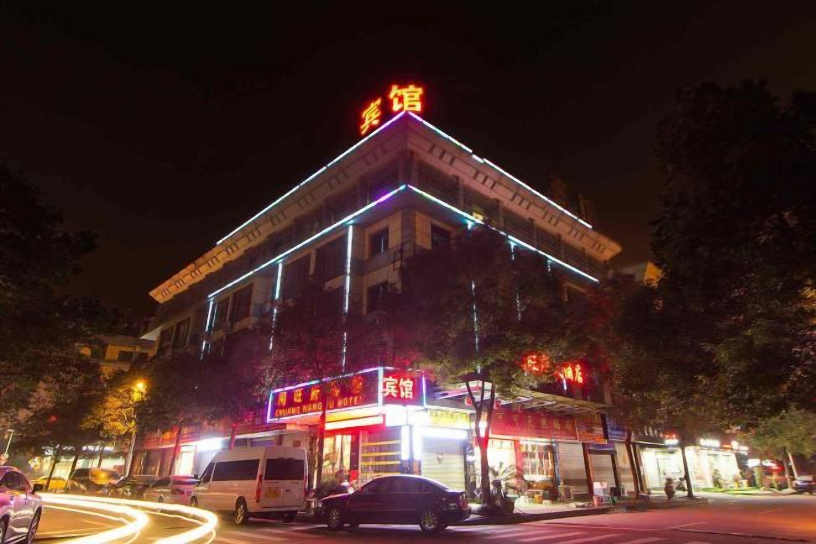 Un hôtel avec une enseigne bien visible, plusieurs boutiques au rez-de-chaussée et un fourgon stationné devant.