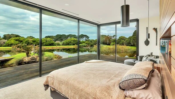Une chambre dotée d’un grand lit, offrant une vue sur un lac, et présentant un design moderne.