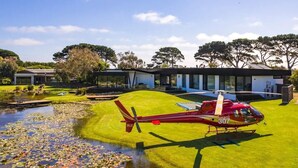 Une maison moderne avec un hélicoptère garé sur la pelouse.