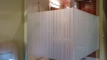 Ein modernes Badezimmer mit Glasabtrennung, einer Duschkabine und einer kleinen Leseecke mit einem Buch.