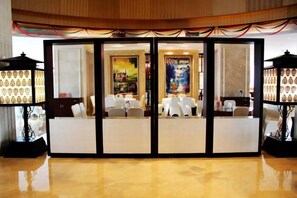 Un vestíbulo de hotel con una recepción, zona de estar y lámparas decorativas.