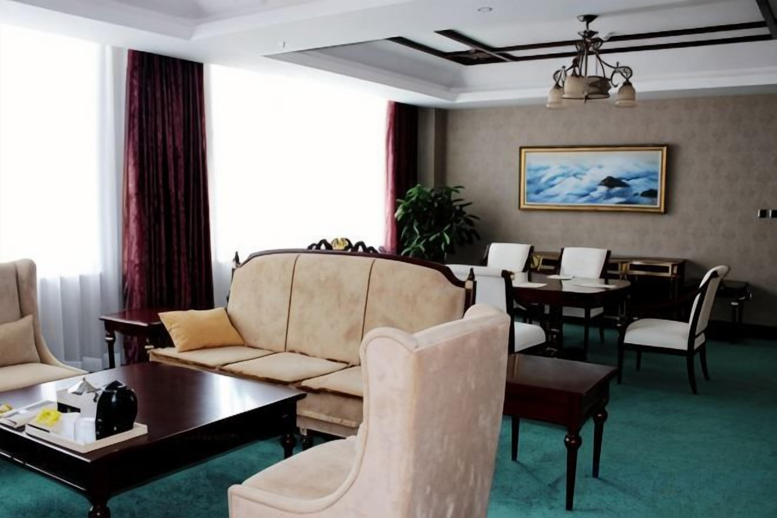 A hotel room with a sofa, armchairs, a dining table, and a painting on the wall.