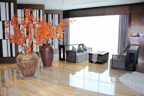 A modern living room with a large vase of orange flowers, a sofa set, and a fireplace. - Haishanghai Hotel (Xingcheng)