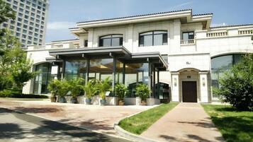 A modern building with a covered entrance, large windows, and a well-maintained lawn.