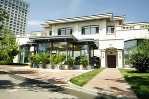 Un edificio moderno con entrada cubierta, ventanas amplias y césped cuidado.