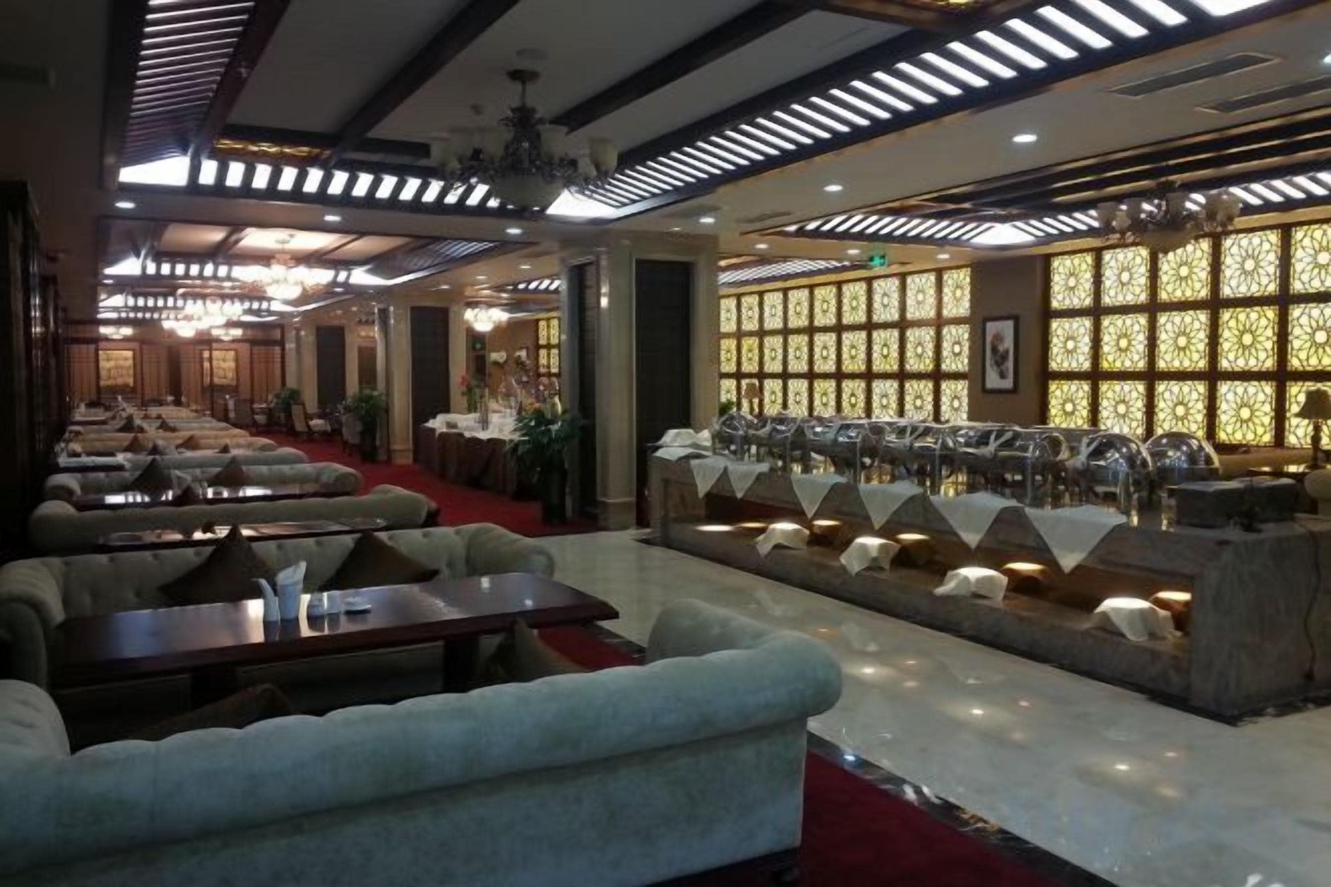 En restaurant med flere spiseborde og stole, et barområde og en siddeplads med sofaer.