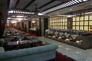 Un restaurante con varias mesas y sillas, una zona de bar y un área de descanso con sofás.