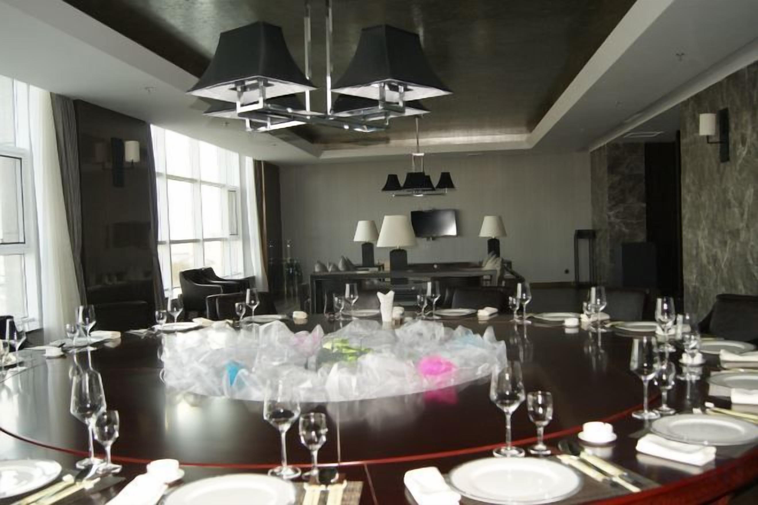 A conference room with a round table set for a meeting, equipped with chairs, a television, and a large window.