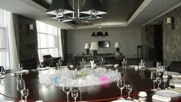 A conference room with a round table set for a meeting, equipped with chairs, a television, and a large window.