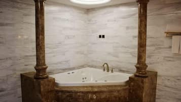 Un baño con pared de mármol, una bañera independiente y una lámpara en el techo.