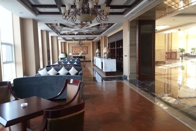 A hotel lobby with seating areas, a reception desk, and a chandelier.