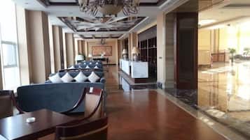 A hotel lobby with seating areas, a reception desk, and a chandelier.