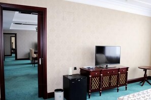 A hotel room with a television, a minibar, and a small table. - Haishanghai Hotel (Xingcheng)