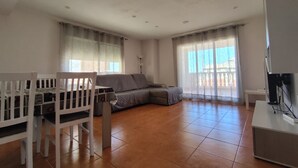 Een woonkamer met een bank, een eettafel met stoelen en een tv-meubel.