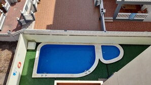 Zwembad op het dak met een groen terras en witte relingen.
