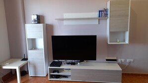 Een moderne woonkamer met een flatscreen televisie, een witte tv-meubel en een boekenkast.