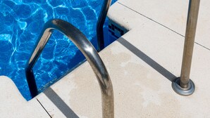 A swimming pool with clear blue water and metal pool ladders.