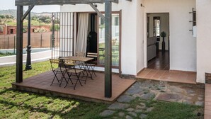 A two-story house with a patio area featuring a pergola and a table.