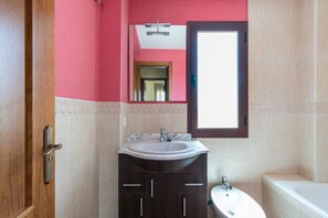 A bathroom with a sink, mirror, and bathtub.